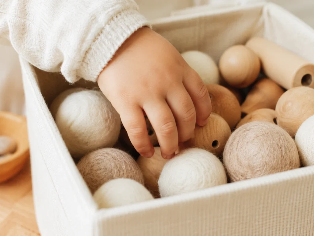 Kinderhand greift in eine Stoffbox, Inhalt halb sichtbar.