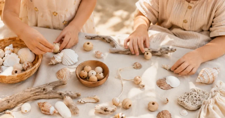 Strandtisch mit Muscheln, Treibholz, Holzperlen, Kinderhände sortieren. Sonniges Licht, Sandfarbe.